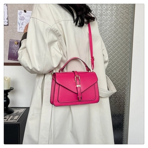 Sac bandoulière magenta avec boucle fer à cheval dorée porté par un mannequin