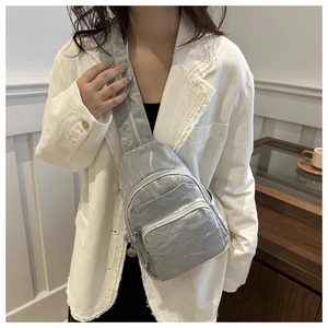 Close-up of silver metallic crinkle fabric texture and zippers on a versatile chest bag