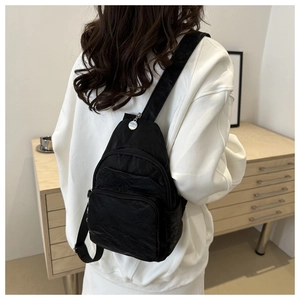 Detail of black nylon chest bag with adjustable strap on a white hoodie model
