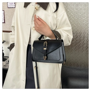 Détails d'un sac bandoulière en cuir noir avec ferrures dorées et poignée supérieure