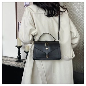Sac à bandoulière noir moderne porté par un mannequin dans un intérieur minimaliste