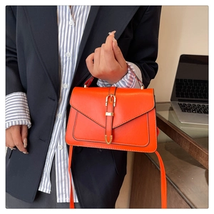 Détail d'un sac à main en cuir orange vif avec boucle dorée et bandoulière élégante