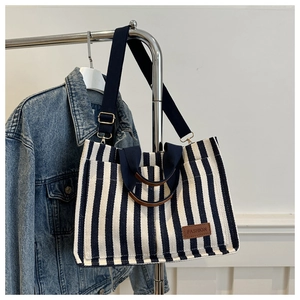 Detailed view of blue and white striped canvas tote bag with brown leather fashion tag