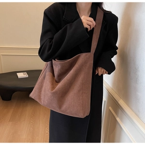 Vue détaillée d'un grand cabas en daim marron avec une large bandoulière minimaliste