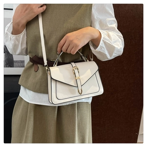 Détail d'un sac à bandoulière blanc structuré avec fermoir doré en fer à cheval
