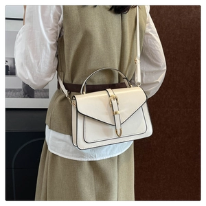 Détail du sac bandoulière rétro blanc cassé avec boucle dorée sur tenue de mannequin