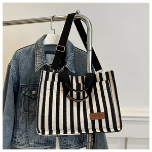 Detail of striped canvas tote with brown ring handle and fashion leather patch