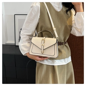 Sac à main beige chic avec fermoir doré porté par un mannequin élégant