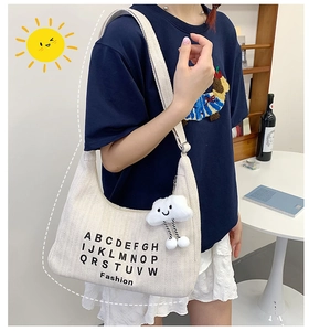 Detail of white corduroy tote bag with black letters fashion print and plush cloud charm