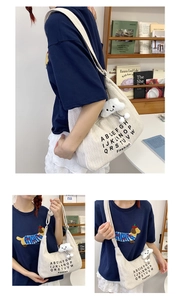 Close-up of minimalist cream canvas tote bag with fashion lettering and plush cloud charm