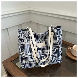 Blue and white patterned canvas tote bag with leather handles on a wooden table