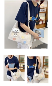 Detail of cream textured tote bag with colorful heart patches and plush cloud charm
