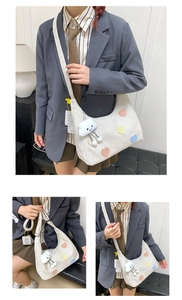 Detail of white canvas tote bag with colorful heart patches and cloud plush charm decoration