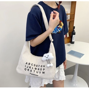 Detail of off-white canvas tote bag featuring black lettering and a plush cloud charm