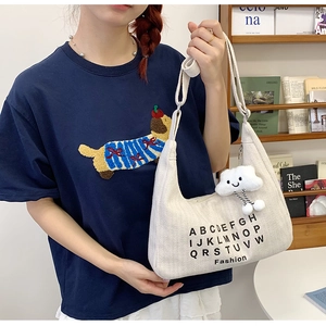 Minimalist canvas tote bag with alphabet print and cloud charm shown on model