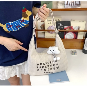 Detail of off-white canvas tote bag with black letters and a soft white cloud charm