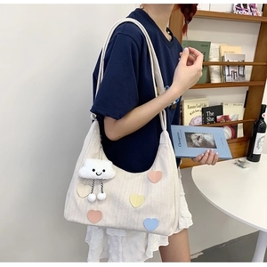 Detail of canvas tote bag with heart patches, rope strap and plush cloud charm