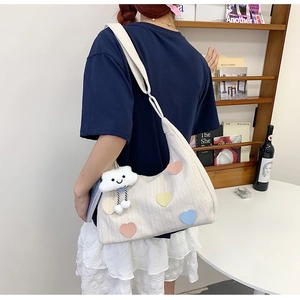 Detail of cream canvas tote bag with colorful heart patches and cloud charm accessory