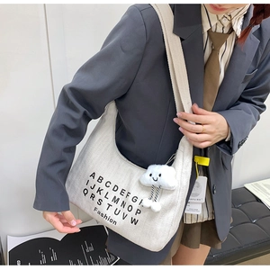 Close-up of minimalist canvas hobo bag with letter print and plush cloud charm detail