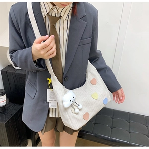 Detail of off-white tote bag featuring colorful heart patches and cloud plush charm detail