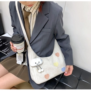 Detail of canvas hobo bag with heart patches and a plush cloud charm accessory