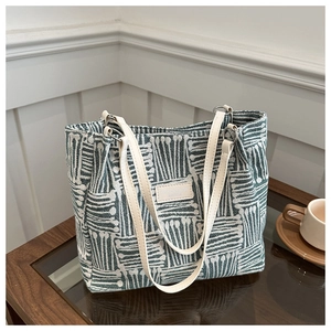 Detail of green striped canvas tote bag with fashion label and leather handle