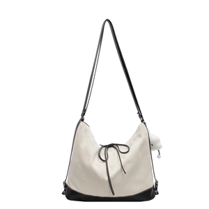 Minimalist canvas tote bag with black leather bow and white plush pendant charm