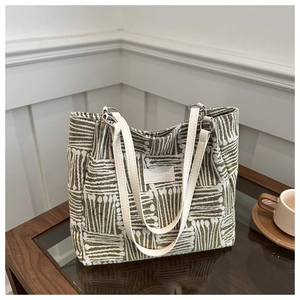 Detail of green and white striped canvas tote bag with fashion leather tag and straps