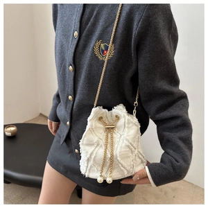 Dettaglio borsa a secchiello in denim trapuntato con catena dorata e perle sul cordoncino