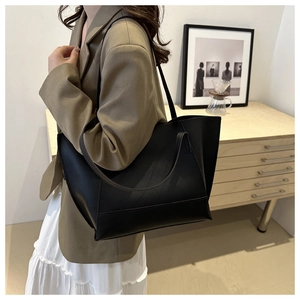 Détail du grand sac cabas noir minimaliste avec bandoulières en cuir porté par un mannequin