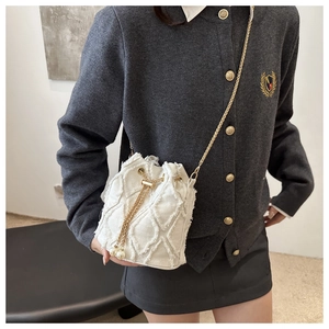 Dettaglio borsa a secchiello in denim bianco con trama trapuntata, catena oro e perle