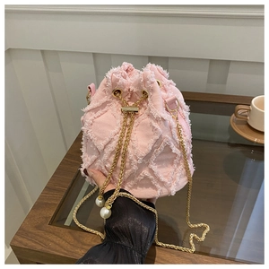 Dettaglio borsa a secchiello in denim rosa con trama trapuntata, catena oro e perle