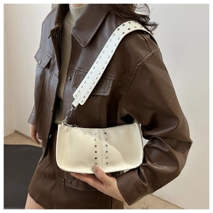 Gros plan d'un sac bandoulière beige vintage avec rivets argentés et large bandoulière