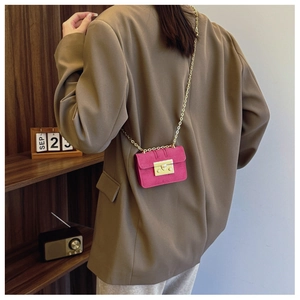 Detailed back view of a mini rose pink crossbody bag with a gold chain strap on a model