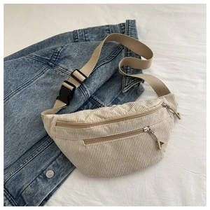 Detail of beige corduroy waist bag showing double zipper pockets and soft ribbed texture