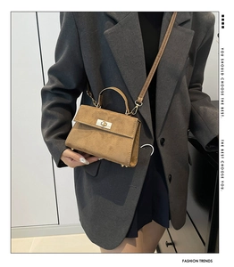 Détail du mini sac bandoulière en daim marron avec fermoir rotatif doré et poignée haute
