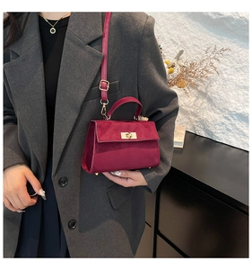 Détail d'un sac à main en velours rouge vin avec fermoir doré et fini texturé
