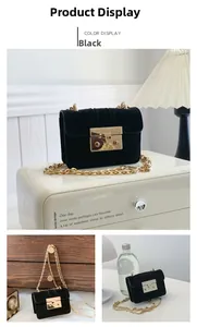 Detail of black suede crossbody bag with gold square push-lock and chain strap