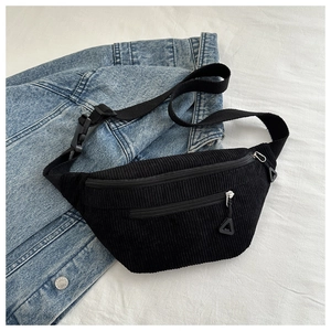 Detail of black corduroy chest bag with textured fabric and two zipper compartments