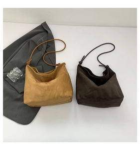 Close-up of minimalist suede hobo bags in brown and camel with knotted cord straps