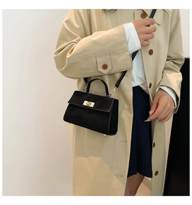 Détail du sac bandoulière noir avec fermoir doré et texture en cuir mat lisse