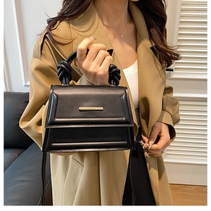 Elegant black faux leather crossbody bag with unique knot handle and gold metal detail