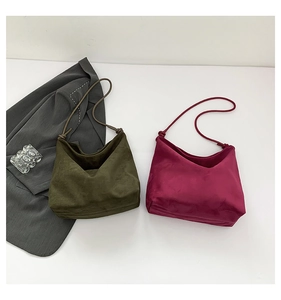 Detail of minimalist suede shoulder bags in olive green and berry red with knotted straps