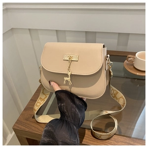 Detail of beige crossbody bag with golden deer pendant and jacquard wide strap