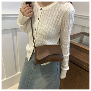 Deep brown leather underarm bag shown with a white knit cardigan for a stylish look