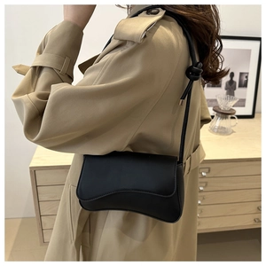 Detail of black leather underarm bag with wavy flap design and knotted strap decoration