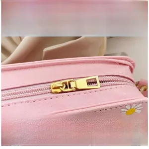 Close-up of golden metal zipper on pink floral PU leather bag with daisy patterns