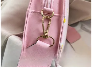 Detail view of pink crossbody bag with daisy prints and gold metal strap hook