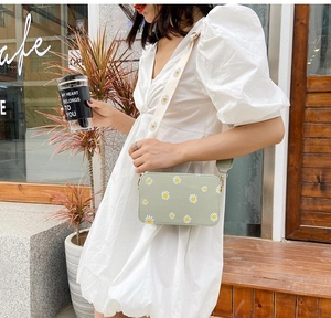 Detail of floral daisy print small square bag with wide shoulder strap in light green