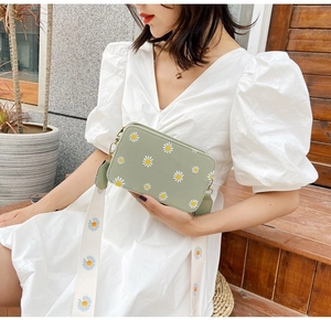 Detail of light green floral crossbody bag with a wide daisy pattern fabric strap